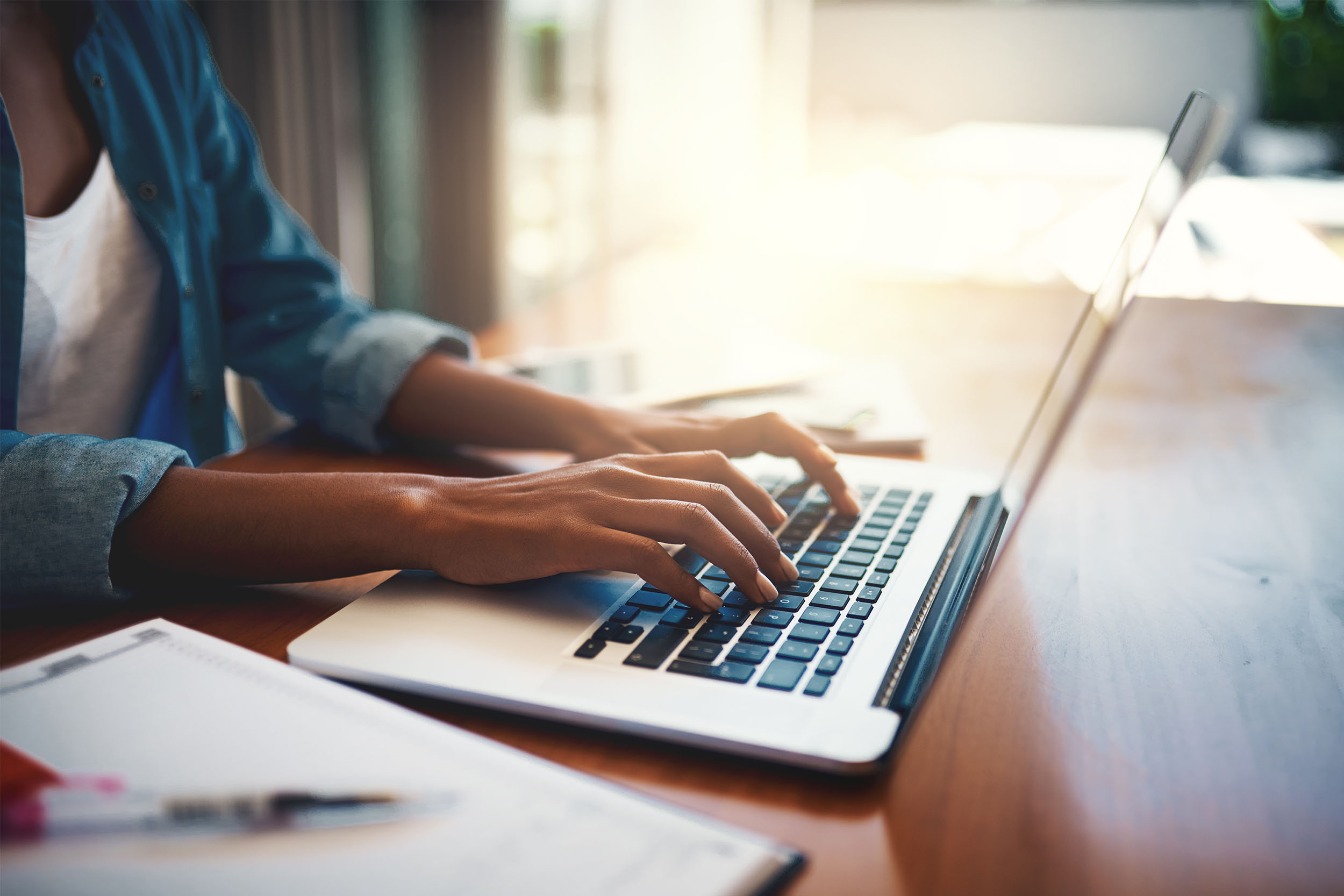 A businessman in an office environment is diligently working on his laptop, actively typing on the keyboard, utilizing modern technology.