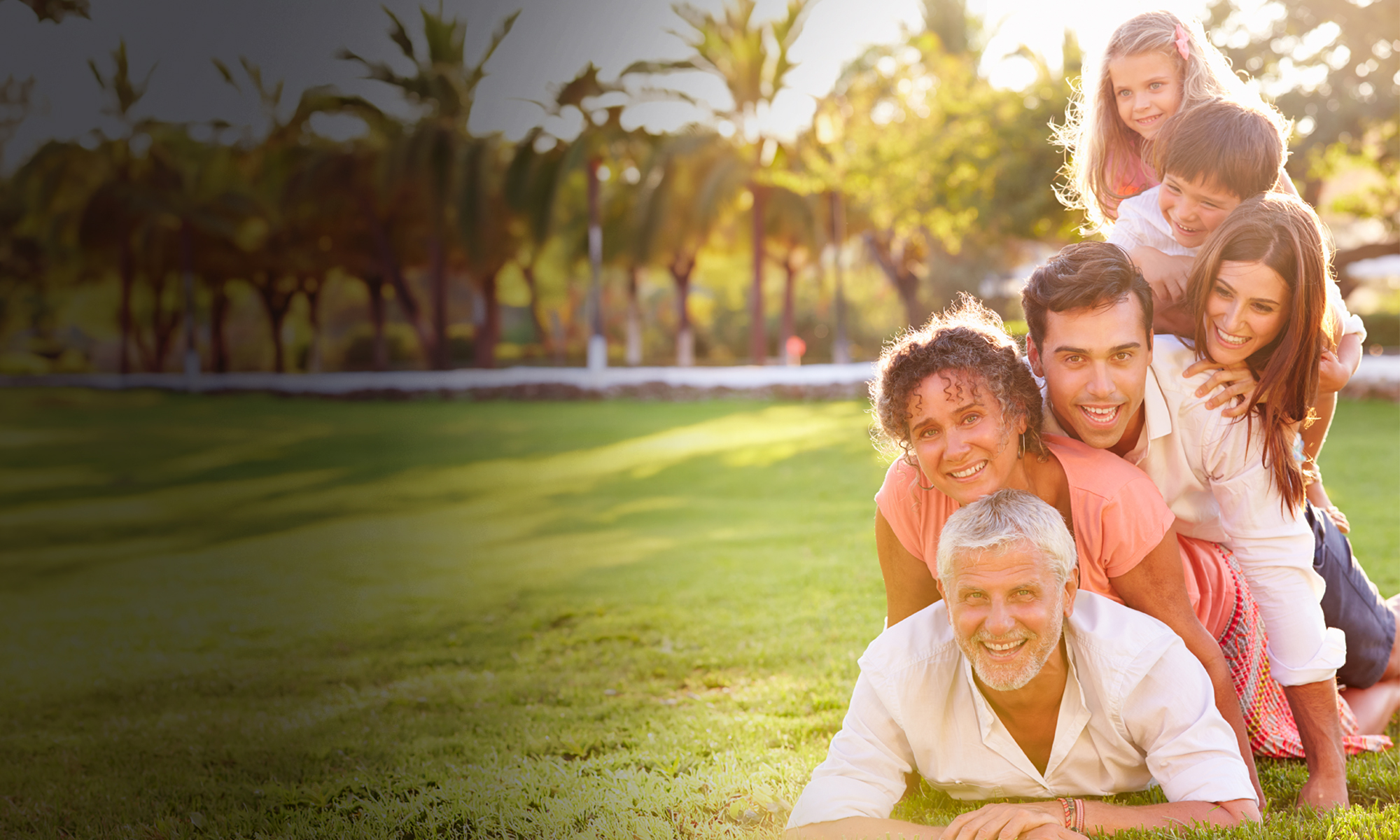 Family posing for a photo while lying on top of  oe another in a pyramid pose