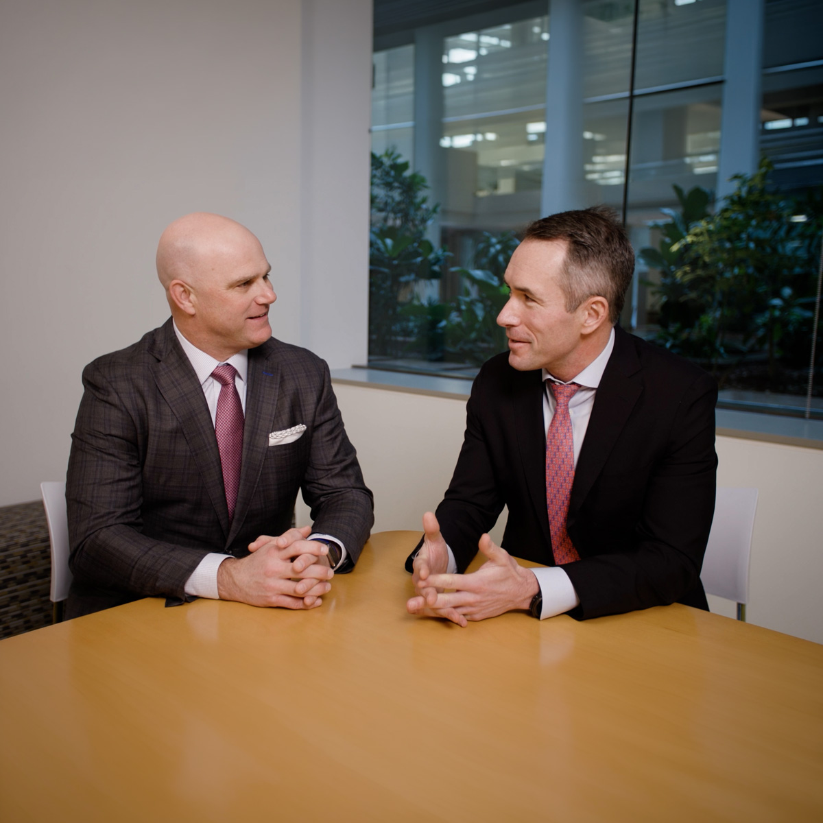 Group of business professionals in formal attire collaborating in a modern office meeting room setting.