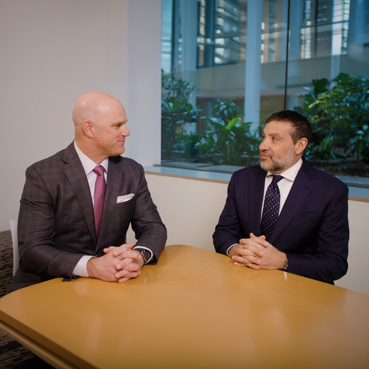 Group of business professionals in formal attire collaborating in a modern office meeting room setting.