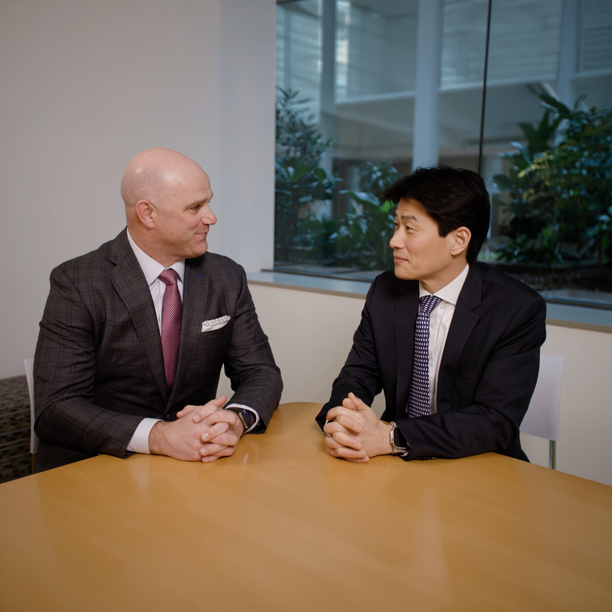 Group of business professionals in formal attire collaborating in a modern office meeting room setting.