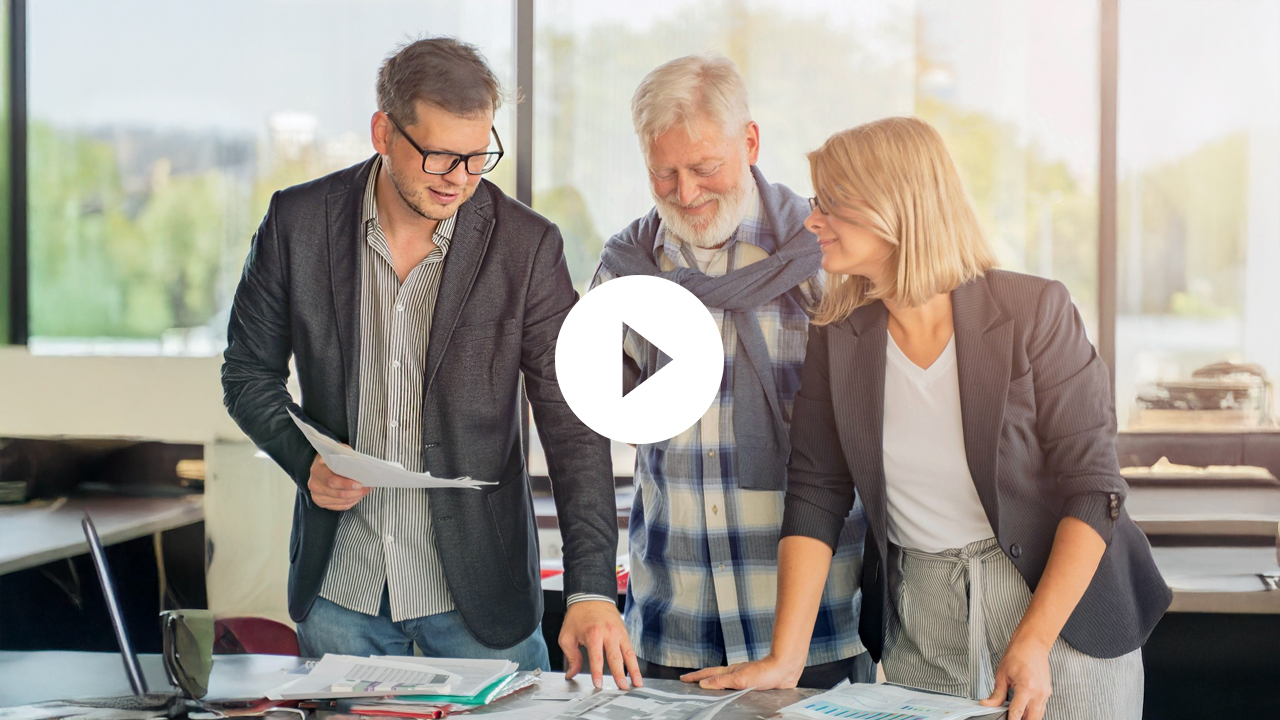 A senior couple engages in a professional discussion indoors, highlighting teamwork and collaboration in a business setting.