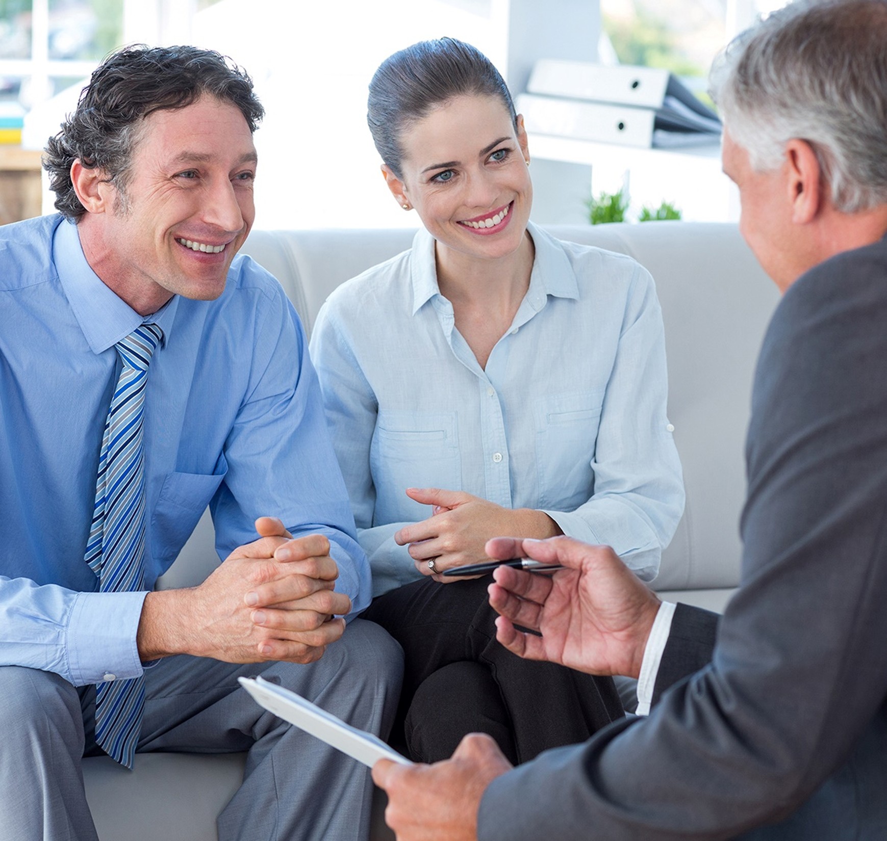 Two clients meeting with a financial advisor in an office setting, discussing investment or financial planning options.
