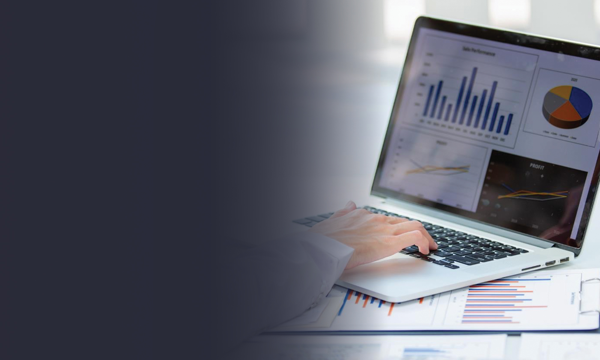 Person using a laptop displaying financial charts and performance dashboards, with printed reports and graphs on a desk.