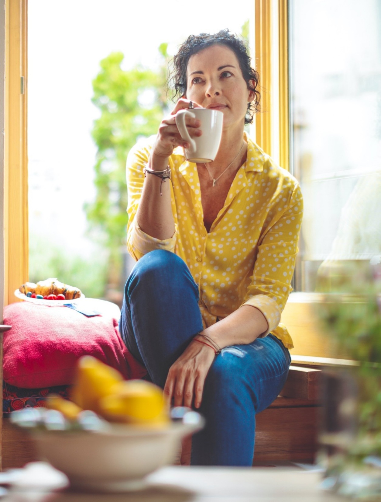 A young woman enjoys fresh fruit in a modern kitchen, highlighting a moment of healthy living in a home setting.
