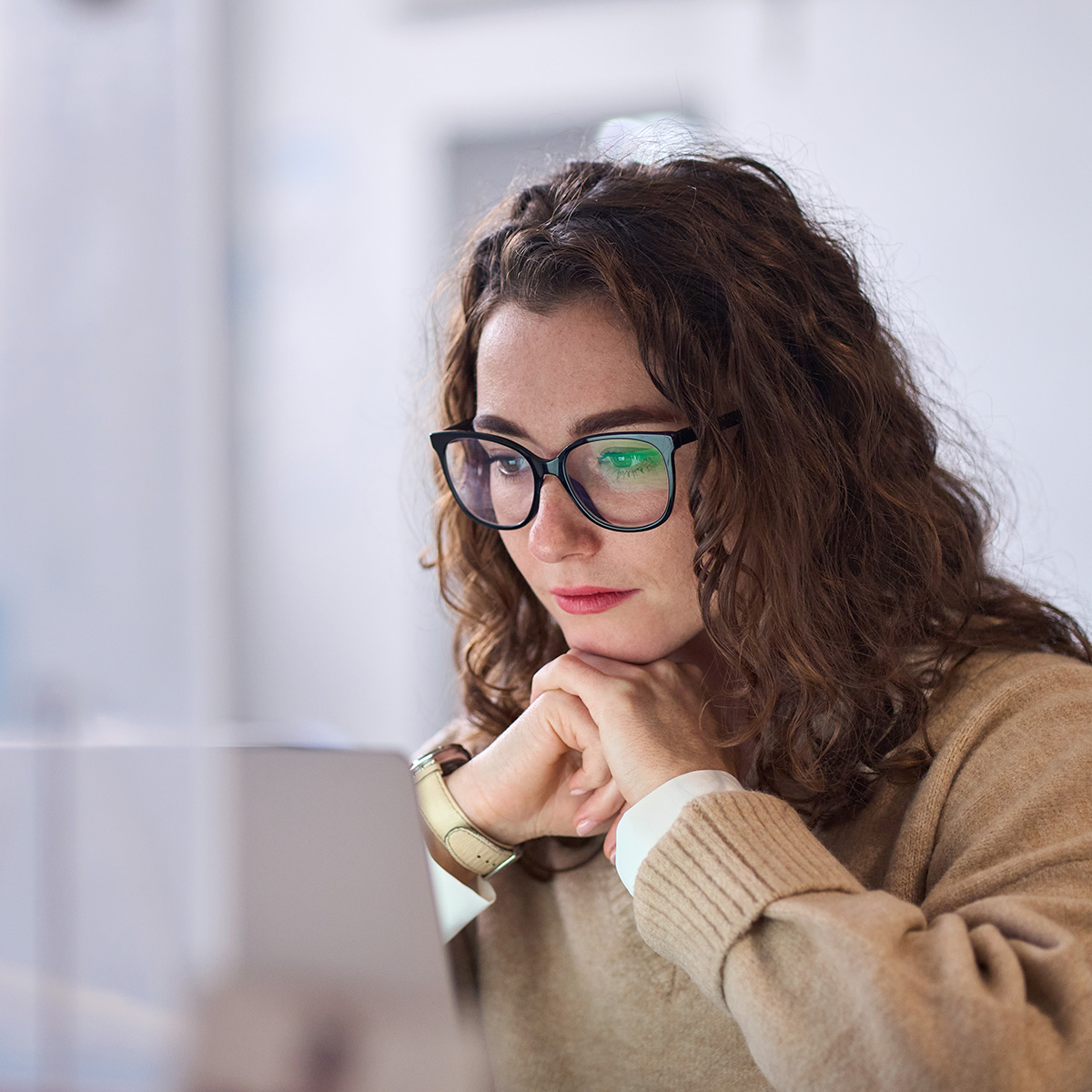 Square business photo of a woman with glasses at a call center, reading client records, thinking on patient support tasks.