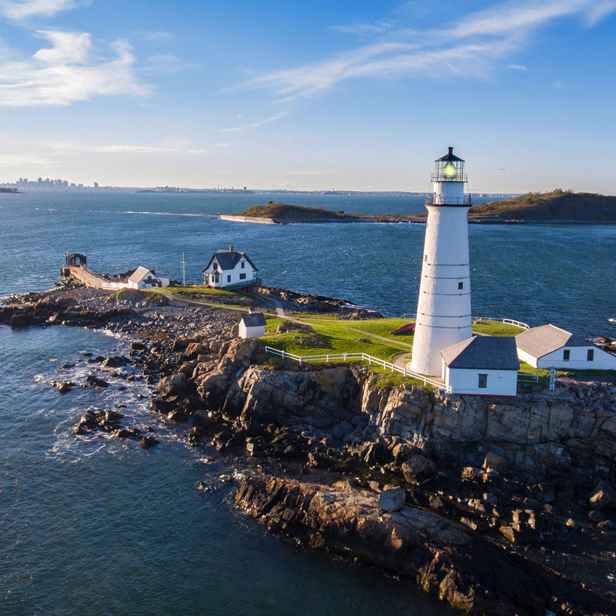 A coastal lighthouse stands tall by the serene ocean under a clear blue sky, guiding vessels with its steady beacon of light.