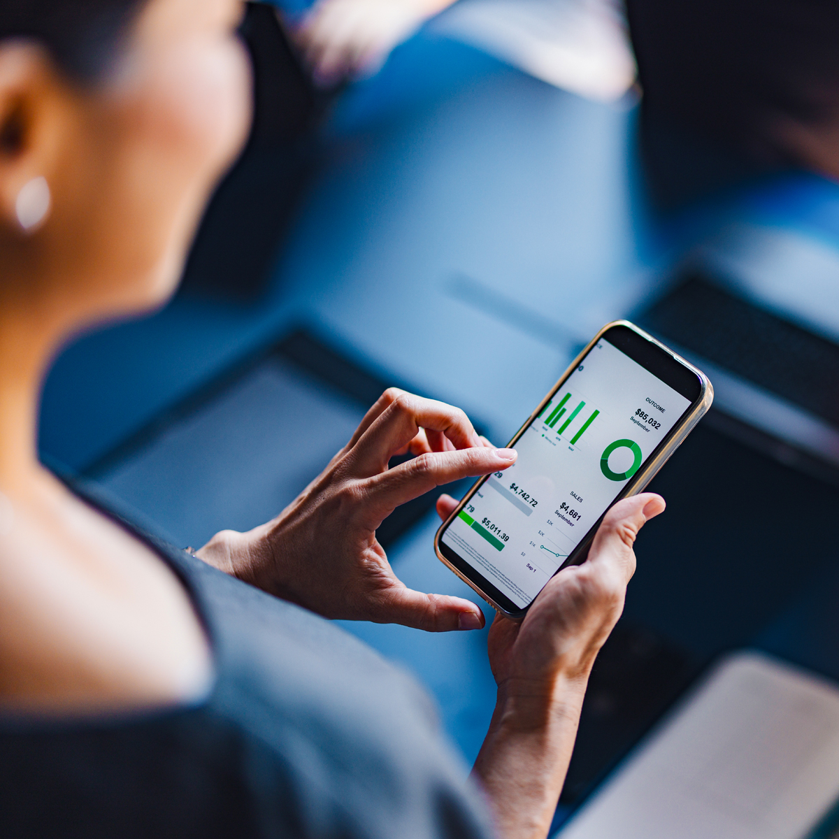 A man and woman using a smartphone in a professional setting, symbolizing mobile communication and finance technology.