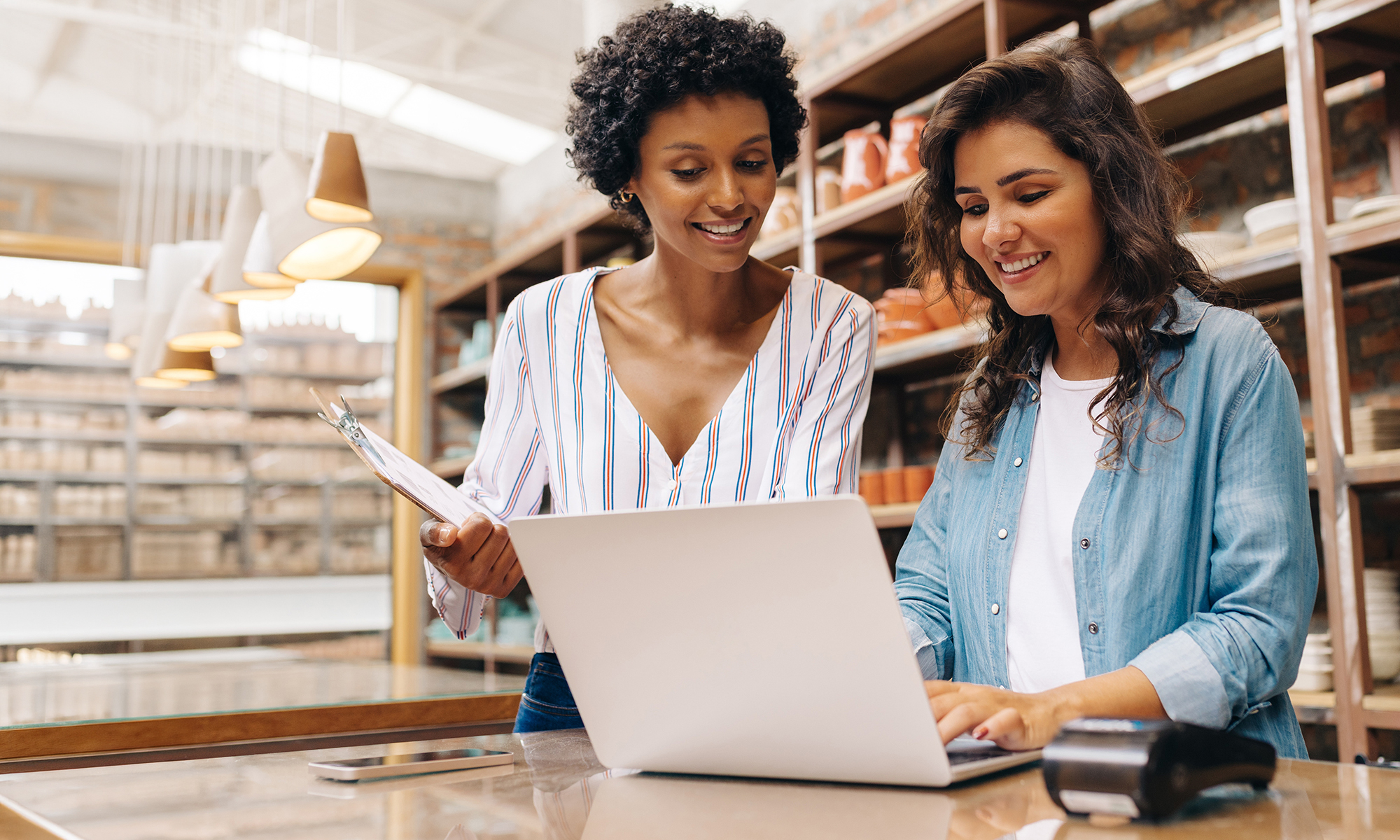 Two business women review a document on a laptop. 