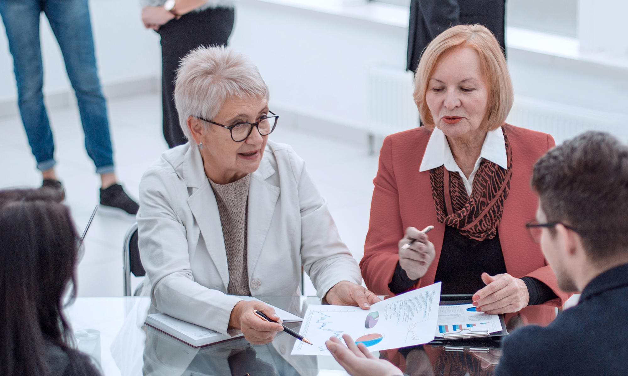 A group of business people meet around a table reviewing documents