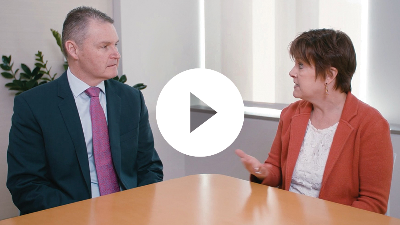 A professional woman leads a discussion with colleagues in an office setting, using a laptop to present key business insights.