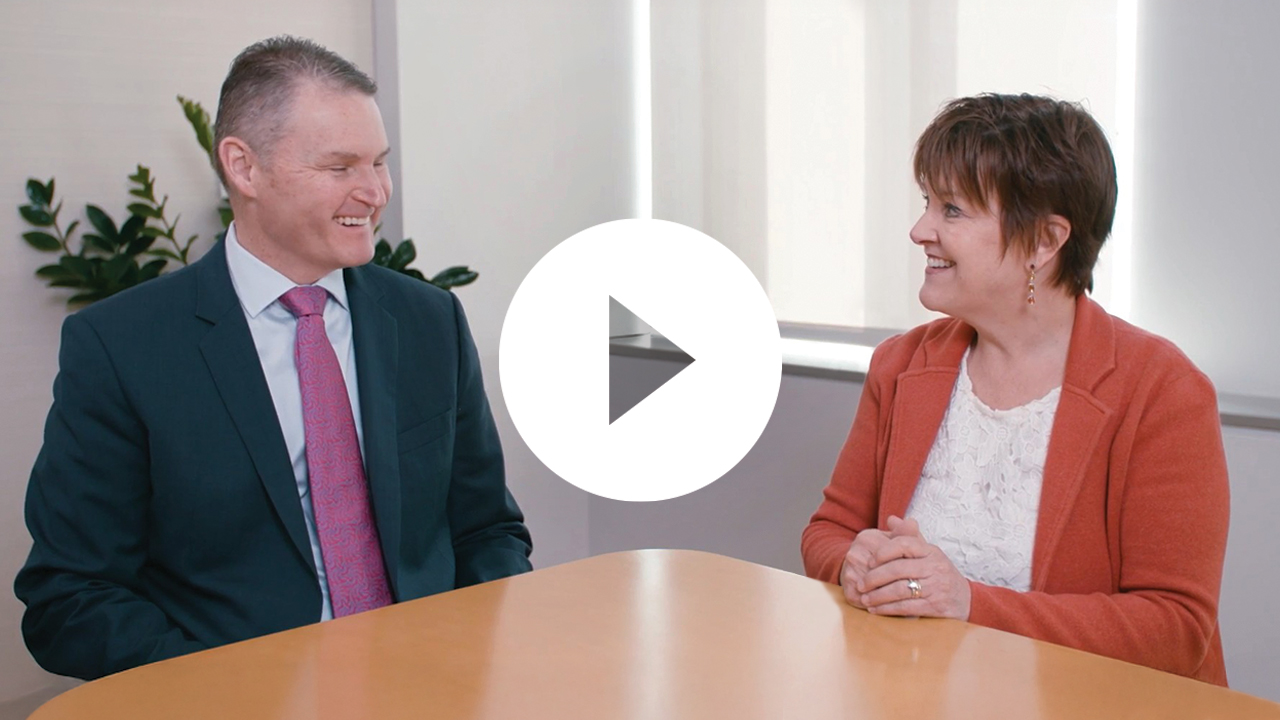 A group of professionals, including a businesswoman and businessmen, collaborate during a meeting in a modern office.