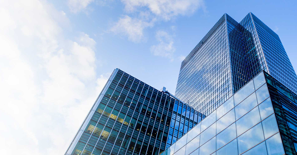 Three themes shaping asset allocation in H2 2023 The modern, blue-tinted glass skyscraper stands out as a beacon of urban business architecture in the bustling city.